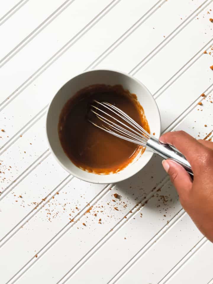 over head shot of dulce de leche in bowl with hand holding a whisk