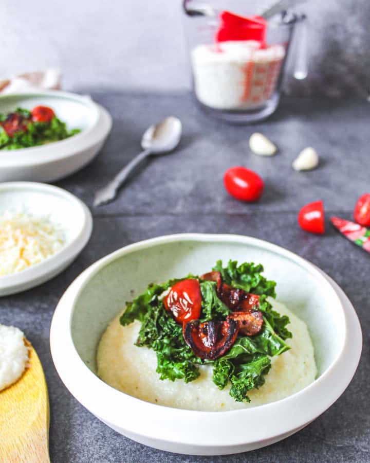 close up of single bowl of cheesy garlic grits with kale in tomatoes