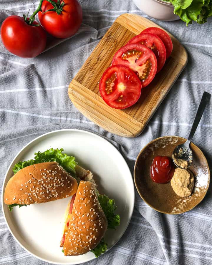 garden herb turkey burger on a plate on a table with tomatoes and condiments