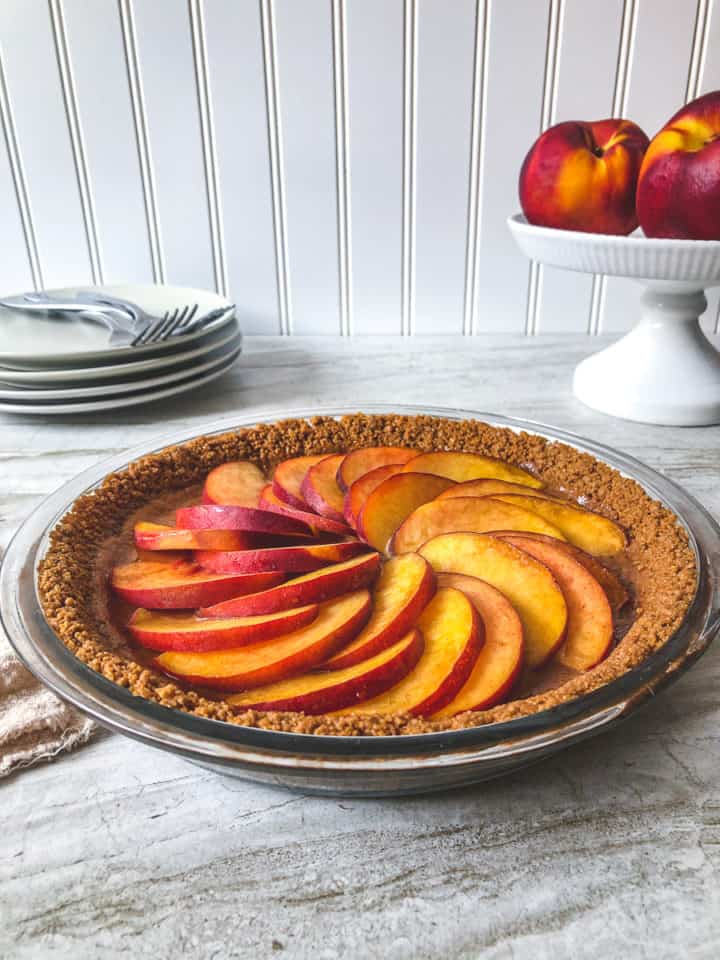 side view of Peach and Dulce De Leche Tart with peaches in background