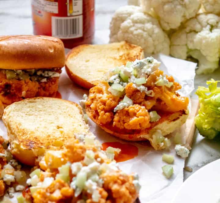 Open faced Buffalo Cauliflower Slider sitting on table surrounded by ingredients
