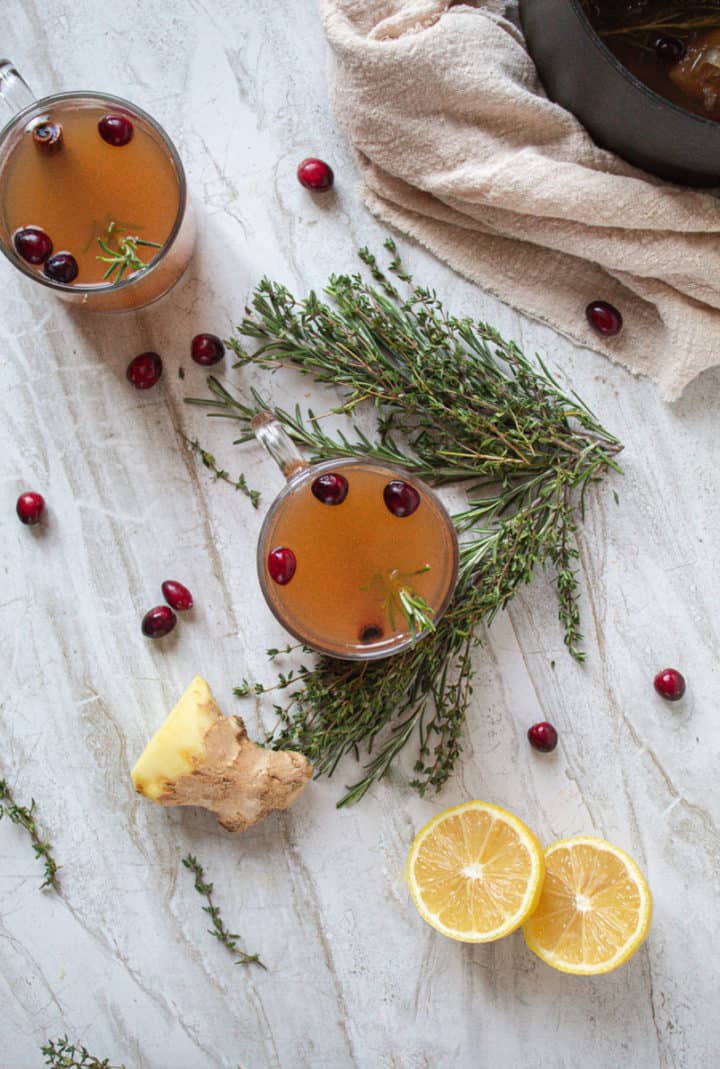 over head shot of herbed mulled cider  surrounded by produce ingredients on marble background