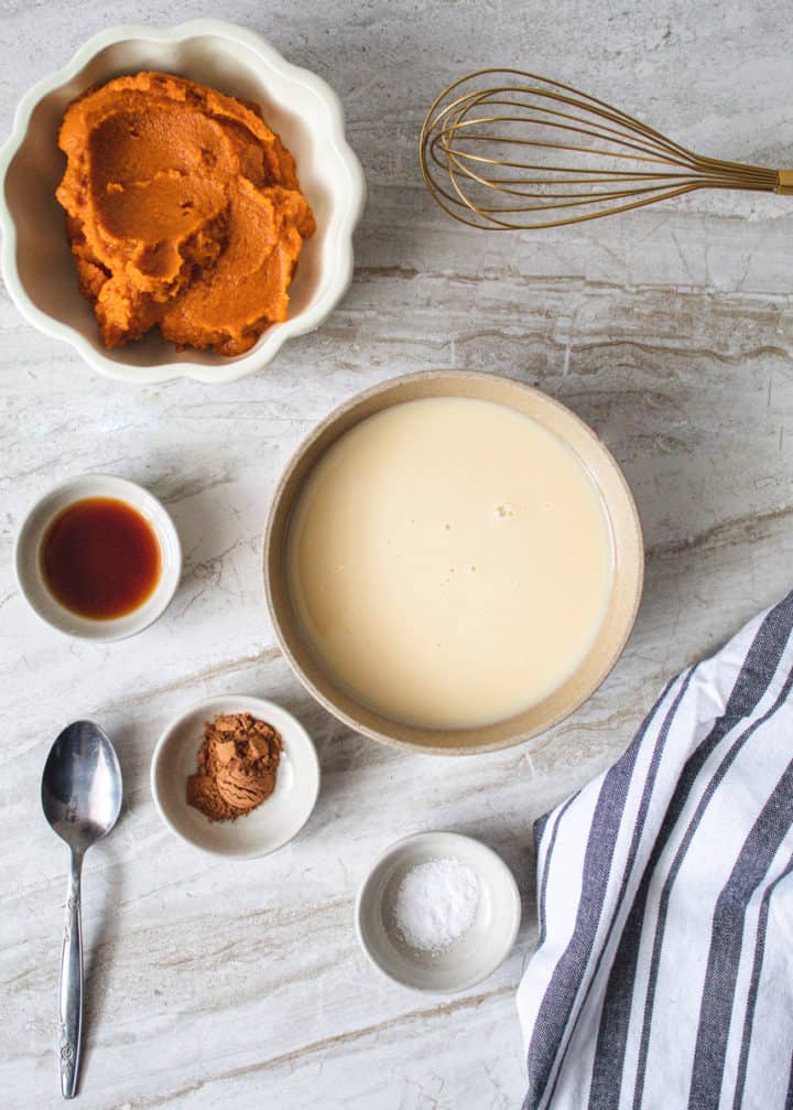 Ingredients to pumpkin ice cream pie in bowls next to a whisk and spoon