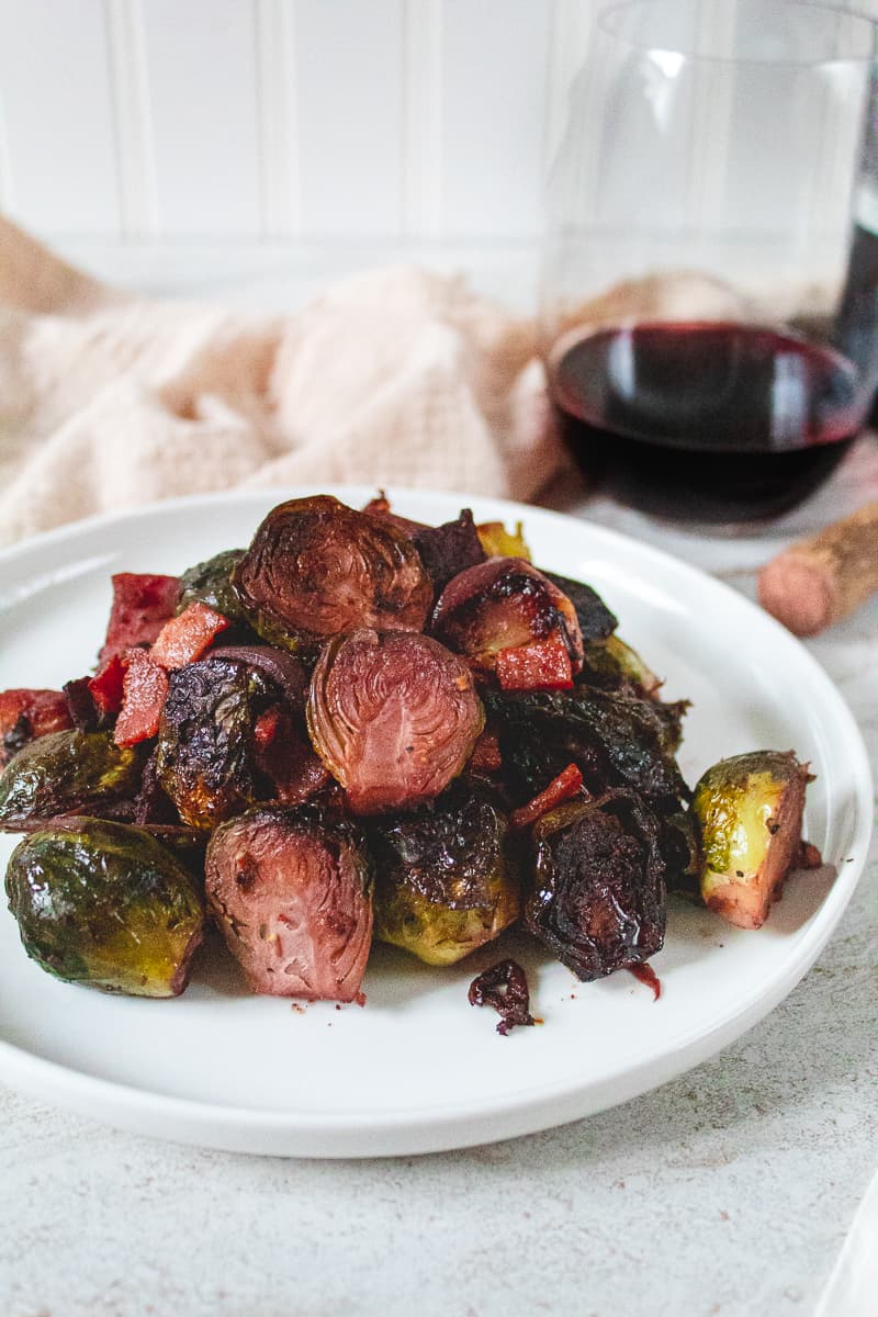 head on shot of red wine brussels sprouts on plate beside a glass a wine