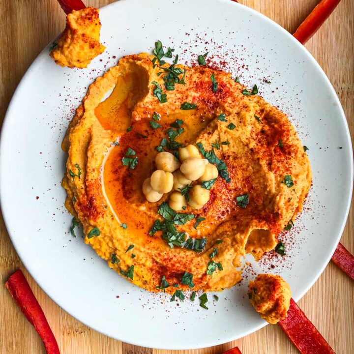 Overhead shot of Smoked Paprika Hummus in bowl surrounded by red pepper slices