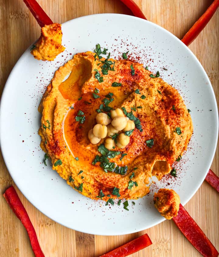 Overhead shot of Smoked Paprika Hummus in bowl surrounded by red pepper slices