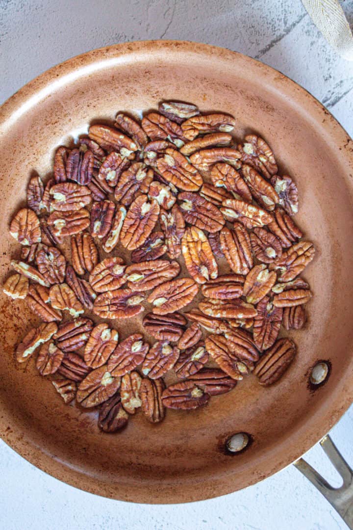 Raw candied pecans in a pan on a white background 