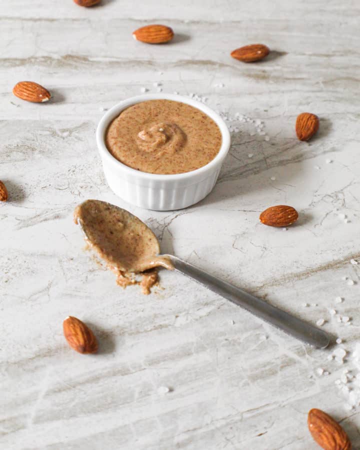 Super easy almond butter in small bowl with spoon surrounded by ingredients