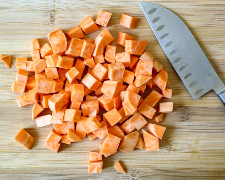 Diced sweet potatoes on cutting board next to knife