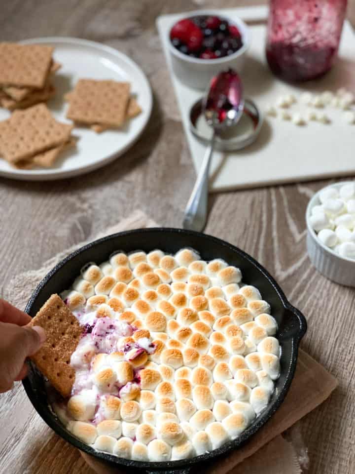 Graham cracker being dipped in pan of marshmallow dip